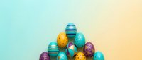 Colorful Easter eggs with decorative patterns arranged in pyramid formation on pastel gradient background for spring holiday celebrations and greeting cards.