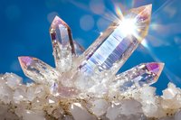 Clear quartz crystal points with rainbow iridescence emerge from white mineral base against blue background, featuring natural light burst and prismatic effects.