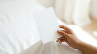 Woman with medium skin tone holding blank white card or paper mockup for branding, greeting, or marketing message display.