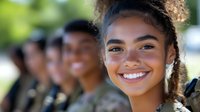 Young African American woman with bright genuine smile and natural curly hair in focus, with diverse group of students blurred in background on sunny day.