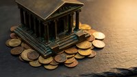 Miniature bronze bank building model surrounded by golden coins on dark wooden surface representing financial savings and investment concepts.