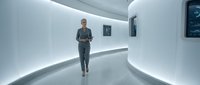 Middle-aged man jogging in futuristic white corridor with illuminated walls and digital displays, wearing athletic gear for fitness and wellness concepts.