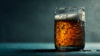 Refreshing cola drink with ice cubes and water droplets on glass surface against dark background for beverage advertising and commercial use.