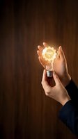 Hands holding a glowing light bulb with a golden gear inside, symbolizing creative thinking, innovation, and engineering solutions.