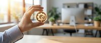 Hand holding golden smiley face emoticon symbol in modern office workspace, representing positive feedback, customer satisfaction, and excellent service rating.