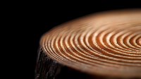 Macro view of wood grain texture showing detailed annual growth rings in natural brown tones against dark background, highlighting organic circular patterns.