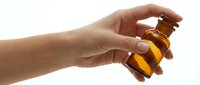 Woman's hand holding amber glass bottle with essential oil, aromatherapy product, isolated on white background for cosmetic and wellness design use.