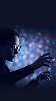 Young Asian woman with glasses reaching toward glowing blue bokeh lights in dark, evoking technology, data, and digital innovation concepts.