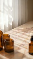Amber glass bottles on marble surface with soft natural sunlight streaming through white curtains creating warm shadows in minimalist spa setting.