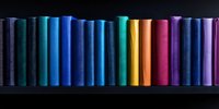 Colorful book spines arranged in rainbow spectrum order on dark wooden shelf, creating vibrant gradient pattern against black background. Perfect for education themes.