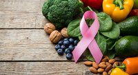Pink ribbon with fresh vegetables and fruits on wooden background promoting breast cancer awareness and healthy nutrition lifestyle.