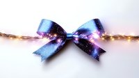 Cosmic galaxy print decorative bow with glitter effect against light background with glowing string lights creating magical festive atmosphere.
