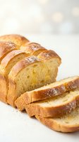 Fresh baked brioche bread loaf sliced on white surface with golden crust and soft fluffy texture for bakery and breakfast concepts.