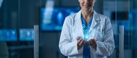 Female doctor in white lab coat holding glowing digital hologram in modern medical facility with blue lighting for healthcare technology concepts.
