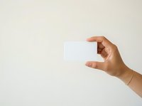Close-up of a hand holding a blank white card against a neutral background, suitable for business cards, gift cards, or promotional material design.