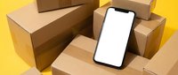 Smartphone with blank white screen surrounded by cardboard shipping boxes on yellow background for delivery and e-commerce mockup applications.