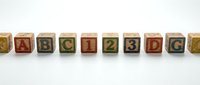 Wooden alphabet blocks arranged in row displaying colorful letters on white background for educational toys and learning materials.
