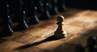 Single wooden chess pawn standing alone on rustic board with dramatic lighting while other pieces remain in shadows symbolizing leadership courage.