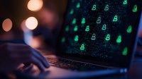 Laptop screen displaying green digital security locks and user icons on dark background with hands typing, representing cybersecurity and data protection concepts.