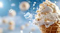 Creamy vanilla ice cream cone with crushed nuts and caramel drizzle splashing with ice cubes against blue bokeh background, frozen dessert macro photography.