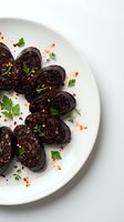 Sliced blood sausage with herbs and spices on white plate, traditional European cuisine appetizer garnished with fresh parsley and paprika powder.