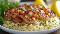 Grilled shrimp with herbs served over seasoned rice pilaf garnished with fresh parsley and lemon wedges for gourmet seafood dining and culinary presentations.