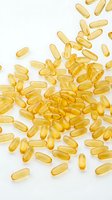 Golden fish oil capsules scattered on white background, representing nutritional supplements, wellness products, and health supplements for dietary use.
