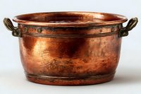 Antique copper basin with ornate brass handles showing rich patina and weathered texture, suitable for rustic home decor or historical displays.