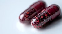 Red transparent capsules with heart pattern design on white background, pharmaceutical medicine concept for healthcare and wellness treatment.