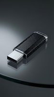 Premium carbon fiber USB flash drive with metallic accents on reflective surface for technology and data storage concepts.