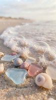 Colorful sea glass and seashells scattered on sandy beach with gentle ocean waves at sunset creating peaceful coastal scene for relaxation and meditation.