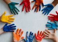 Colorful painted hands forming circle on white background, representing unity, diversity, teamwork and creativity in childhood education and community projects.