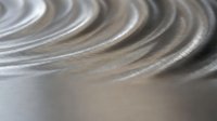 Metallic silver spiral coil with smooth reflective surface creating concentric circular patterns for industrial design and manufacturing concepts.