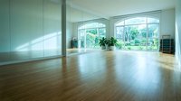 Modern empty room with large windows, wooden floors and mirror wall for yoga, dance studio or fitness space interior design.