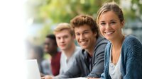 Happy diverse college students studying together outdoors on campus with laptops for education and teamwork projects.
