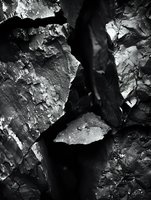 Dark rocky crevice with textured stone walls and deep shadows, shot from above in monochrome. Suitable for geology, nature, and abstract backgrounds.