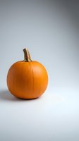 Fresh orange pumpkin with natural stem on clean white background for autumn harvest decorations and seasonal design projects.