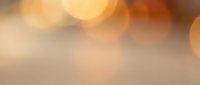 Soft warm bokeh background with blurred golden and amber light circles creating an elegant, out-of-focus atmosphere suitable for overlays and design backdrops.