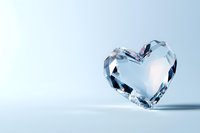 Crystal clear heart-shaped diamond on light blue background, symbolizing love, purity and luxury for wedding or anniversary designs.