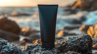 Black cosmetic tube on rocky beach at sunset, natural skincare product packaging mockup against blurred coastal background with golden light.