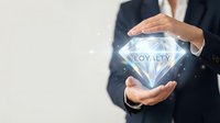 Businessman in dark suit holding glowing diamond with loyalty text, representing customer retention, rewards program, and business value concept for corporate marketing.