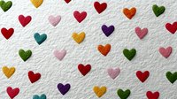Colorful heart pattern on white textured paper background. Romantic love symbols in rainbow colors scattered across surface for Valentine's Day designs.