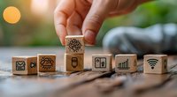 Hand arranging wooden cubes with digital technology and social media icons, perfect for business technology concepts and digital transformation strategies.