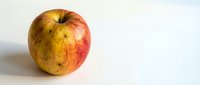 Fresh ripe apple with natural red and yellow skin coloring on clean white background, healthy organic fruit for nutrition and wellness concepts.