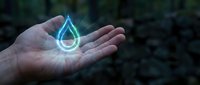 Glowing blue water drop hologram floating above open palm in natural outdoor setting representing clean water conservation and environmental protection technology.