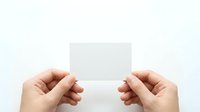 Two hands holding blank white card against neutral background, suitable for business branding, marketing mockups, and promotional material presentations.