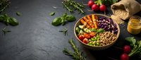 Colorful Buddha bowl with quinoa, chickpeas, purple cabbage, carrots and fresh herbs on dark slate background for healthy meal planning.