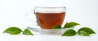Glass cup of amber tea with fresh green leaves on white background, hot beverage for relaxation and wellness, isolated for design use.