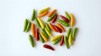 Colorful hot chili peppers in red, green, yellow and orange scattered on white background. Fresh spicy ingredients for cooking and seasoning dishes.