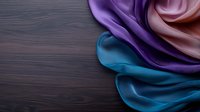 Luxurious silk fabric swatches in turquoise, purple, and pink creating elegant folds and waves against dark wooden background, suitable for fashion design.